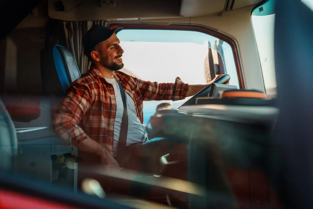 A truck driver fastening their seat belt as a safety measure.